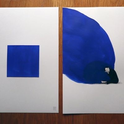 Duas folhas de papel com arte abstrata azul sobre mesa de madeira