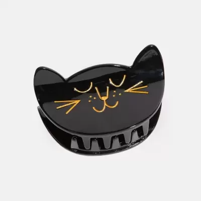 Prendedor de cabelo preto em formato de rosto de gato com detalhes dourados.
