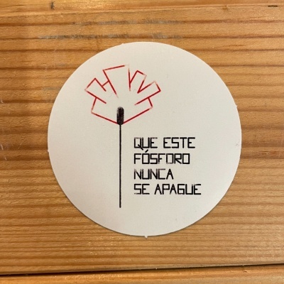 Etiqueta redonda branca com texto e ilustração sobre madeira clara