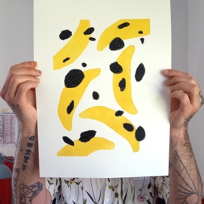 Folha de papel com manchas amarelas e pretas segurada por pessoa tatuada com camisa floral