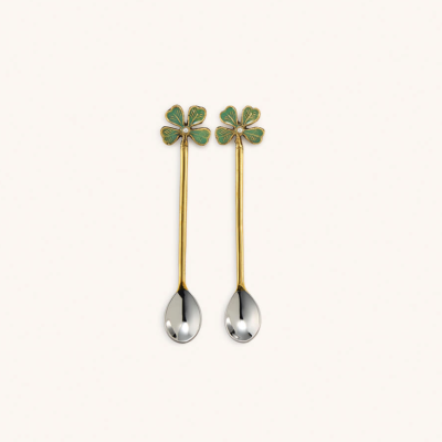 Duas colheres decorativas com flores verdes e cabos dourados sobre fundo branco.