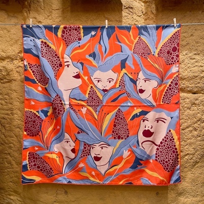 Lenço quadrado colorido com faces femininas e folhas abstratas em tons laranja, vermelho e azul