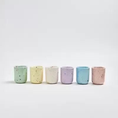 Seis copos de cerâmica coloridos em linha sobre fundo branco