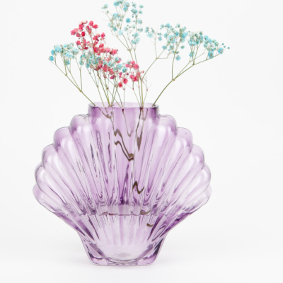 Vaso lilás em vidro com formato de concha e flores pequenas rosa e azul