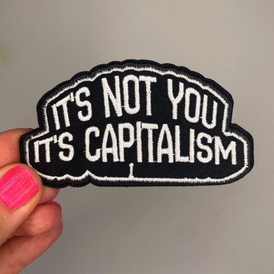 Patch preto bordado com texto branco ITS NOT YOU ITS CAPITALISM