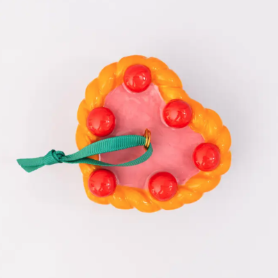 Pingente decorativo em forma de coração com fita verde.