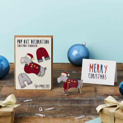 Decoração destacável de Natal em feltro com elefante e texto, em mesa com bolas e prendas.