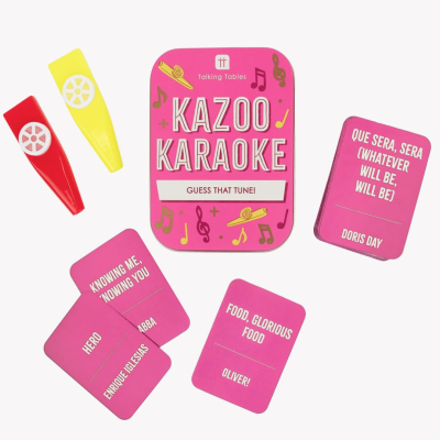 Jogo de cartas Kazoo Karaoke em caixa rosa com kazoos coloridos e cartas com nomes de músicas e artistas