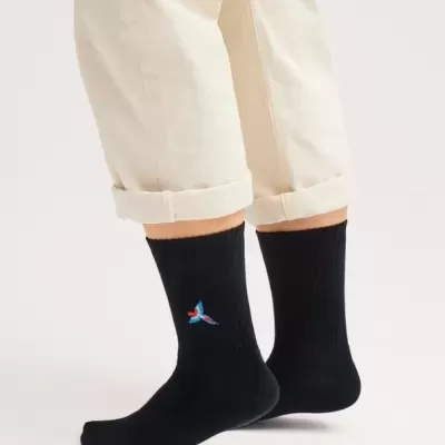 Meias pretas com padrão bordado colorido usadas com calças bege