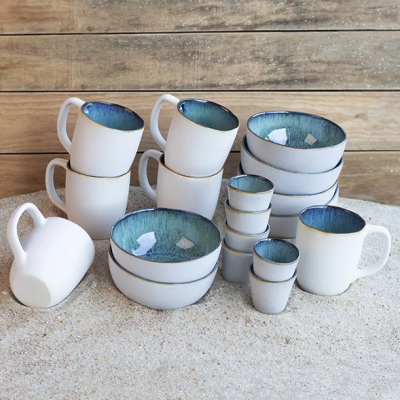 Conjunto de louça branca com interior azul colocado sobre areia