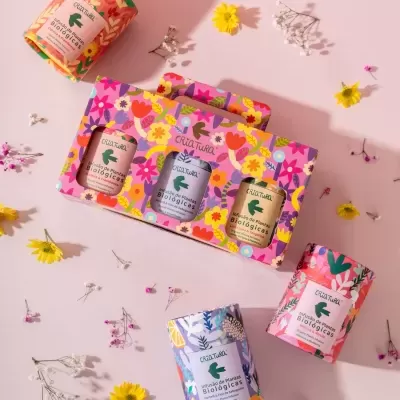 Caixas coloridas de infusão de plantas biológicas Criatura com design floral sobre fundo rosa e flores ao redor