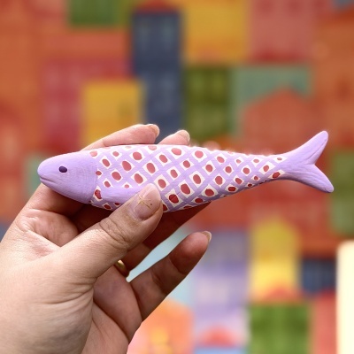 Peixe decorativo lilás com padrão geométrico segurado por uma mão