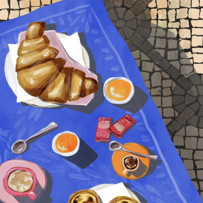 Mesa com croissant, pastéis de nata, café e compotas sobre toalha azul e chão de mosaico.