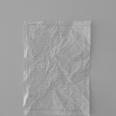 folha de papel branca vincada com linhas e três furos sobre superfície cinzenta