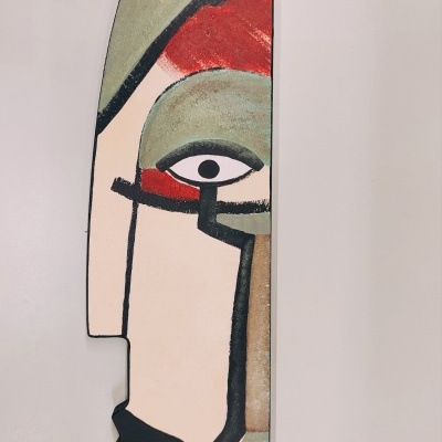 Escultura decorativa abstrata de rosto com cores verde, vermelho, preto e bege