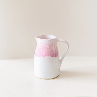 Jarro cerâmico branco com parte superior rosa, com bico e alça, em fundo branco neutro