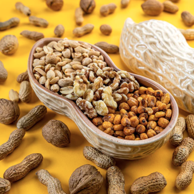 Taça em forma de amendoim com frutos secos variados em fundo amarelo.