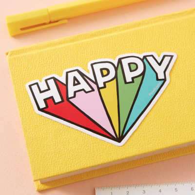 Estojo amarelo com autocolante HAPPY colorido, marcador amarelo e régua branca.