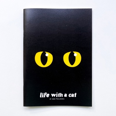 Caderno preto com olhos amarelos de gato e texto na capa