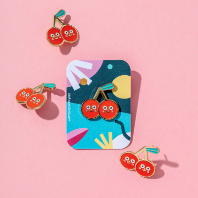 Pins de cereja com rostos sorridentes sobre fundo rosa