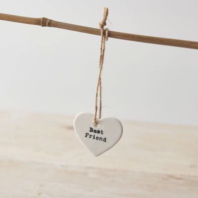 Coração decorativo branco com texto Best Friend pendurado num ramo de madeira