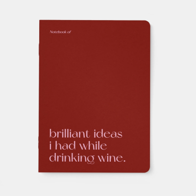 Caderno vermelho com texto branco 'Notebook of brilliant ideas i had while drinking wine.'