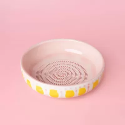 Prato cerâmico rosa com padrão amarelo e textura circular
