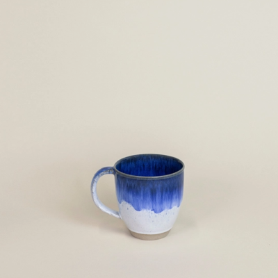 Caneca cerâmica azul e branca com punho em fundo neutro