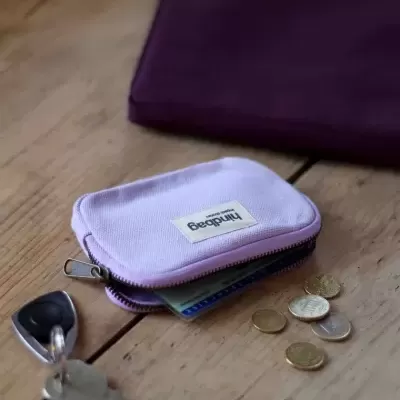 Carteira pequena roxa clara com etiqueta Findbags, chave e moedas em madeira
