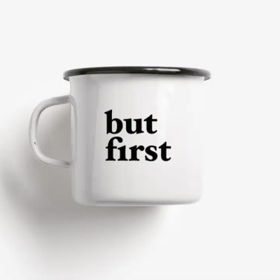 Caneca branca de metal com texto preto 'but first'