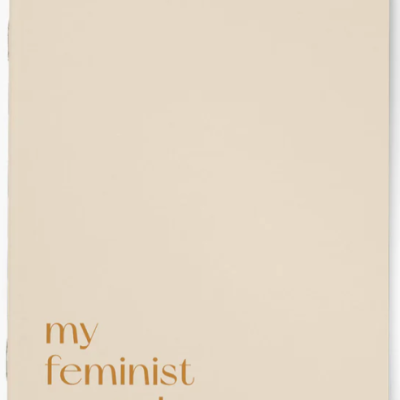 Caderno bege claro com texto dourado 'Notebook of my feminist agenda.'