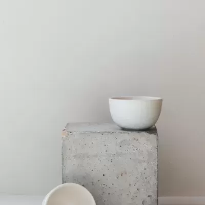 Dois copos/tigelas brancos em cima e em frente a cubo de cimento cinzento