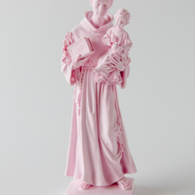 Estátua rosada de figura religiosa com criança e livro