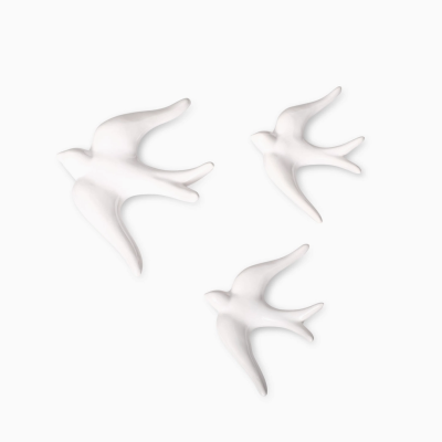 Três esculturas decorativas de pássaros brancos sobre fundo branco