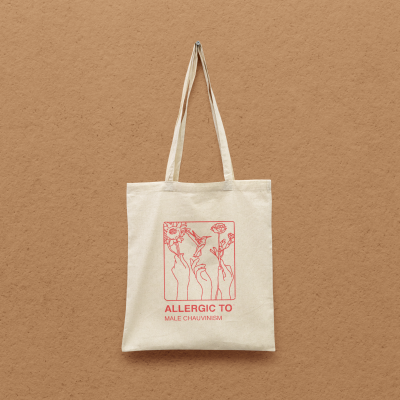 Saco de pano bege com alças e estampa vermelha com texto e desenho de mãos com flores.
