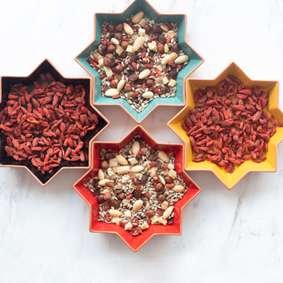 Quatro taças estrela com frutos secos e bagas vermelhas em superfície branca
