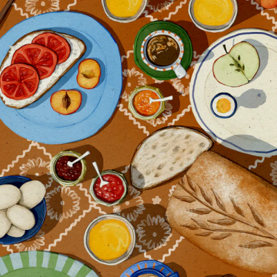 Mesa com alimentos diversos para pequeno-almoço sobre toalha estampada