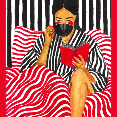 Mulher a ler livro vermelho e beber em chávena preta, com robe às riscas e cobertores às riscas.