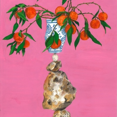 Arranjo de galhos com laranjas e folhas num vaso cerâmico branco com padrão azul sobre pedras empilhadas, fundo rosa.