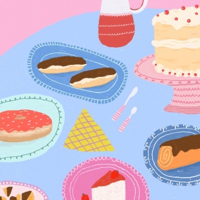 Mesa azul com vários pratos de sobremesas variadas, jarra vermelha e branca e duas colheres de sobremesa em fundo rosa