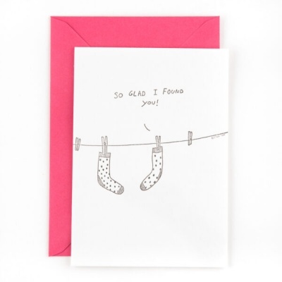 Cartão branco com desenho de meias e texto em inglês, acompanhado de envelope rosa