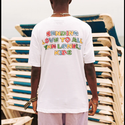 T-shirt branca com texto colorido nas costas perto de espreguiçadeiras na praia