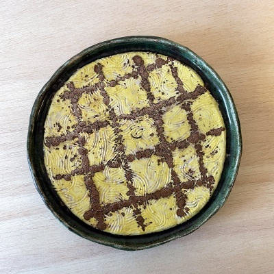 Prato de cerâmica verde com sobremesa amarela decorada com padrão de chocolate