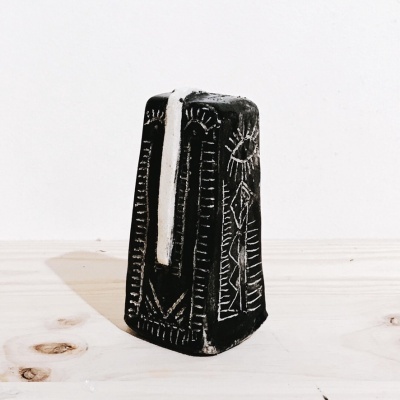 Escultura preta decorativa com entalhes geométricos e figura humana