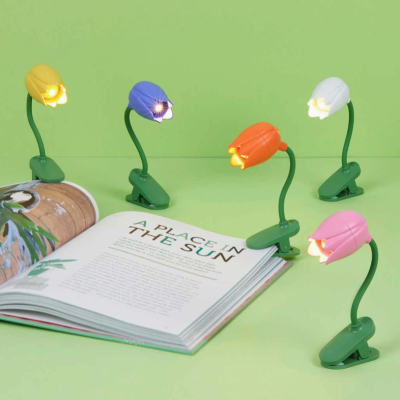 Cinco mini candeeiros florais coloridos iluminados sobre livro aberto em fundo verde.