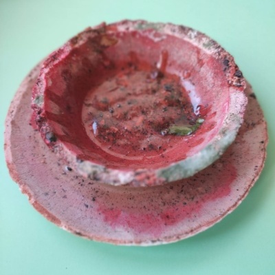 Conjunto de prato e taça de cerâmica vermelhos desgastados sobre superfície verde