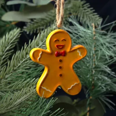 Enfeite de Natal boneco de gengibre amarelo com gravata vermelha pendurado em pinheiro