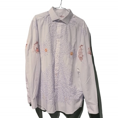 Camisa branca de manga comprida com bordados ferrugem pendurada num cabide