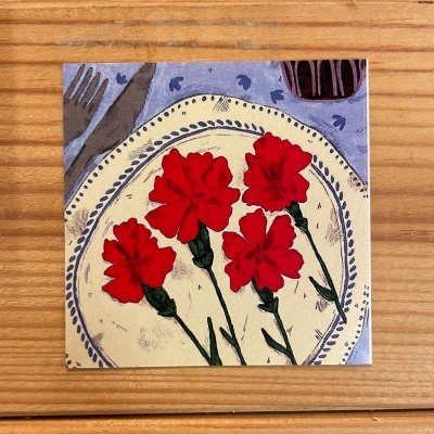 Ilustração de flores vermelhas num prato decorativo em superfície de madeira