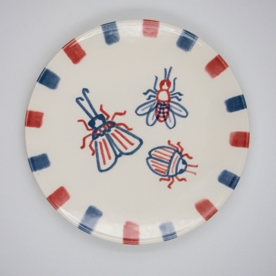 Prato de cerâmica decorado com insetos e borda a quadros vermelhos e azuis